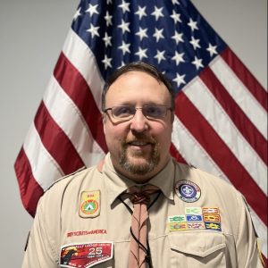 Justin Lewis in Scout uniform in front of US flag